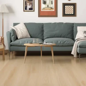 Blue-gray sectional sofa with chaise and a cream armchair around a round wooden coffee table in a bright living room with wall art and a wooden floor.