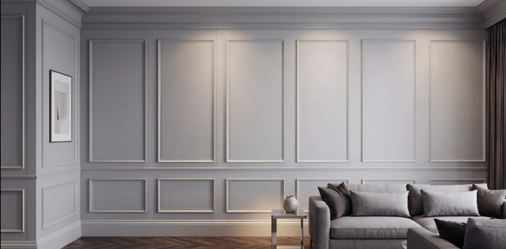 Grey wall with raised panel moulding behind a grey sectional sofa