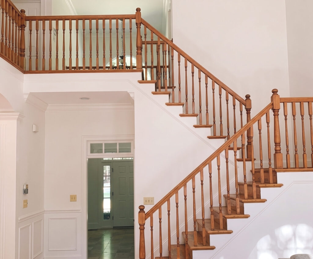 Staircase with orange-stained wood spindles and railing before renovation