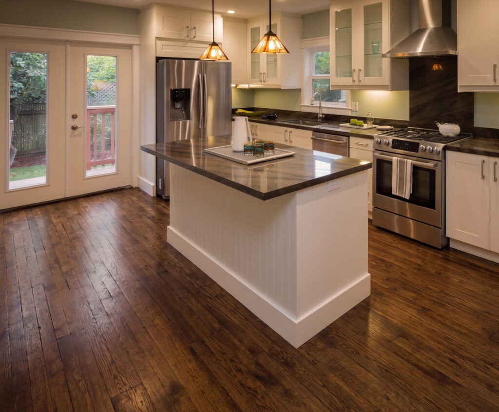 Dark worn hardwood floor in a kitchen before new laminate