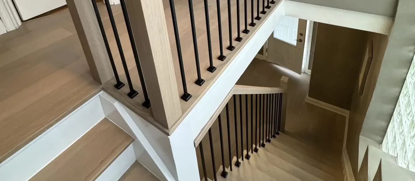 Refinished staircase in Bolton: natural light oak treads with white risers, square oak posts and black iron spindles on the landing