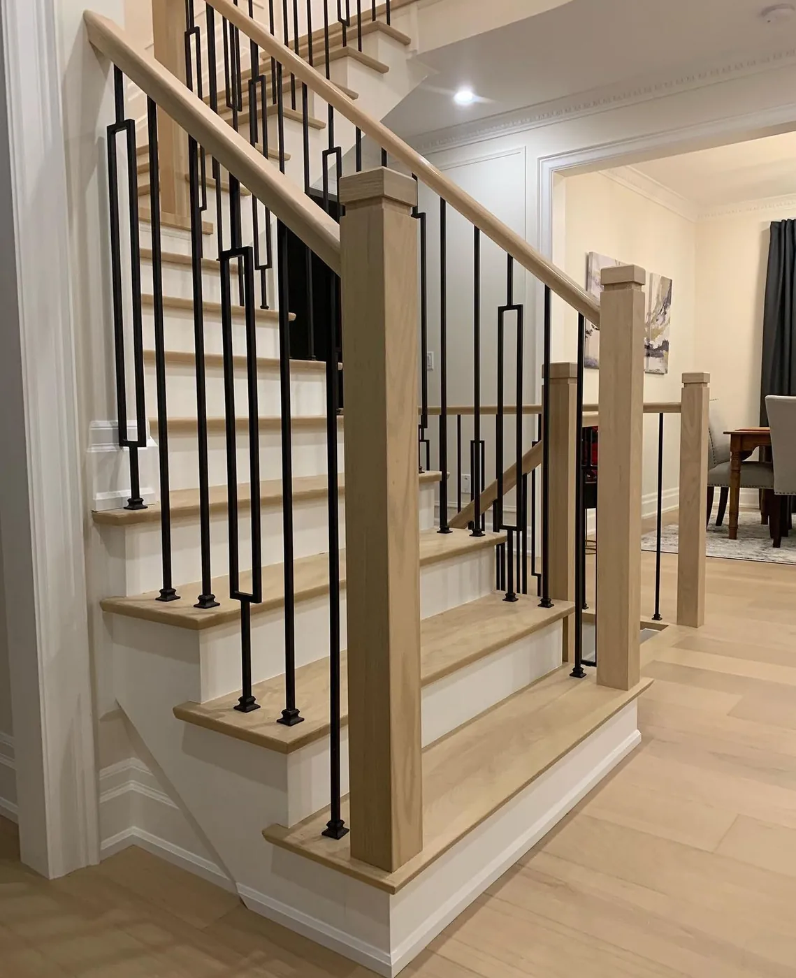 Light natural oak stair treads with white risers, square oak newel posts and black rectangular iron spindles, Lakeshore, Toronto