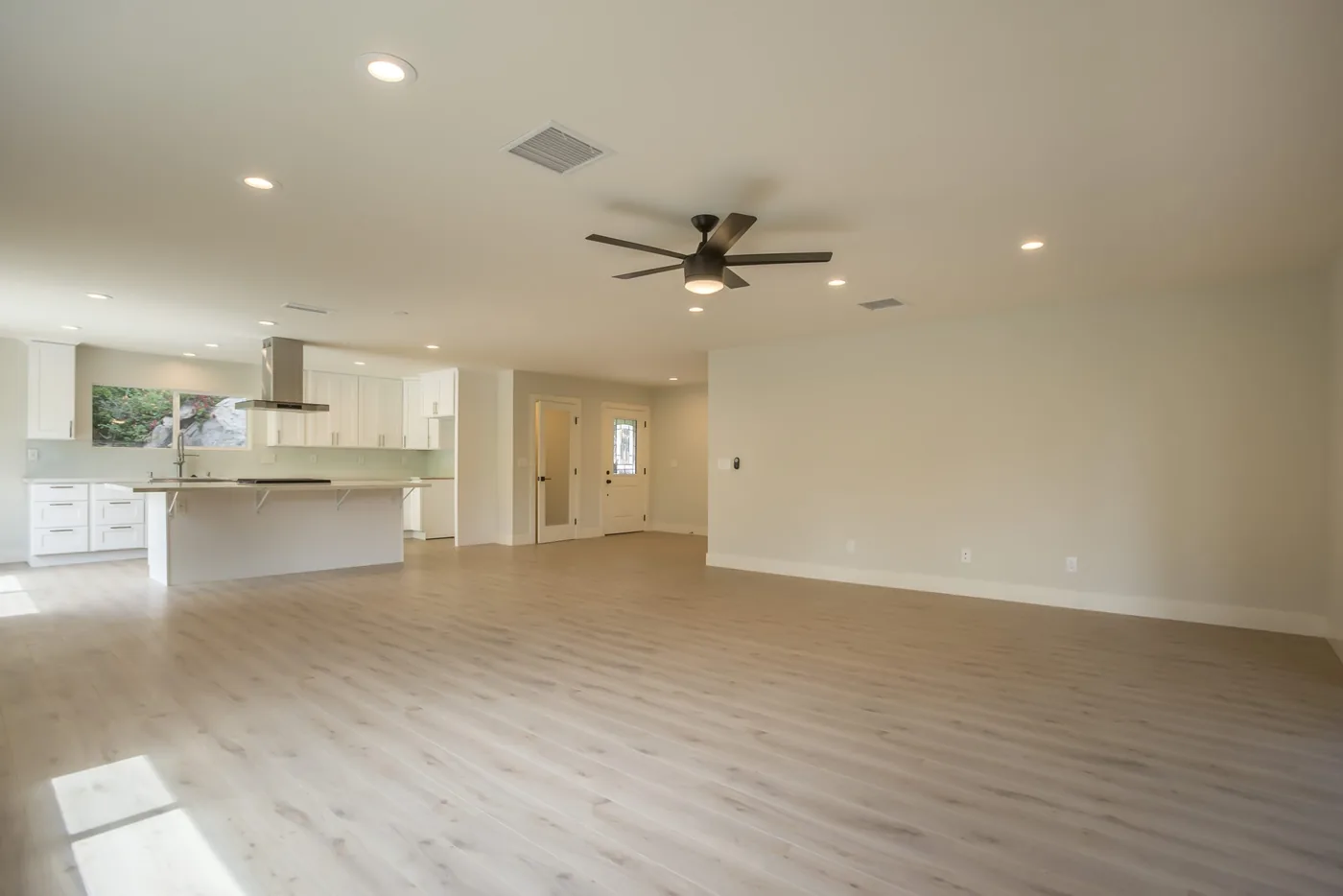 Light grey vinyl plank floor across an open kitchen and living area with a ceiling fan, Toronto