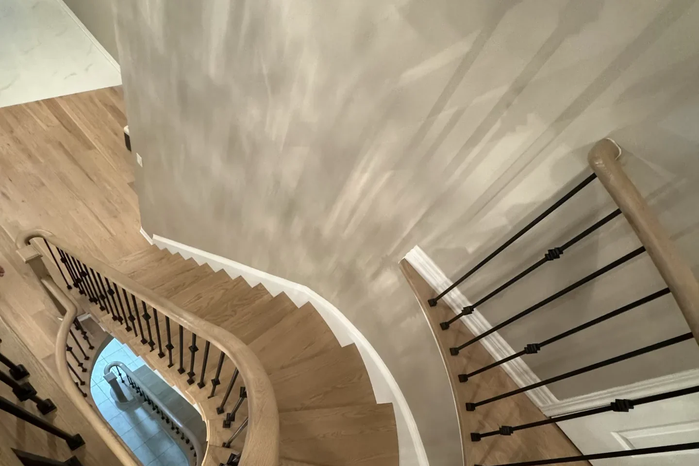 Curved white oak staircase with black iron spindles, seen from the upper landing of a Bolton home