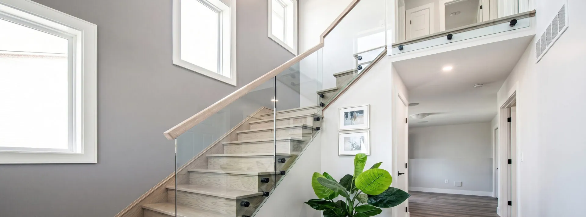 Staircase with glass railing panels and oak handrail
