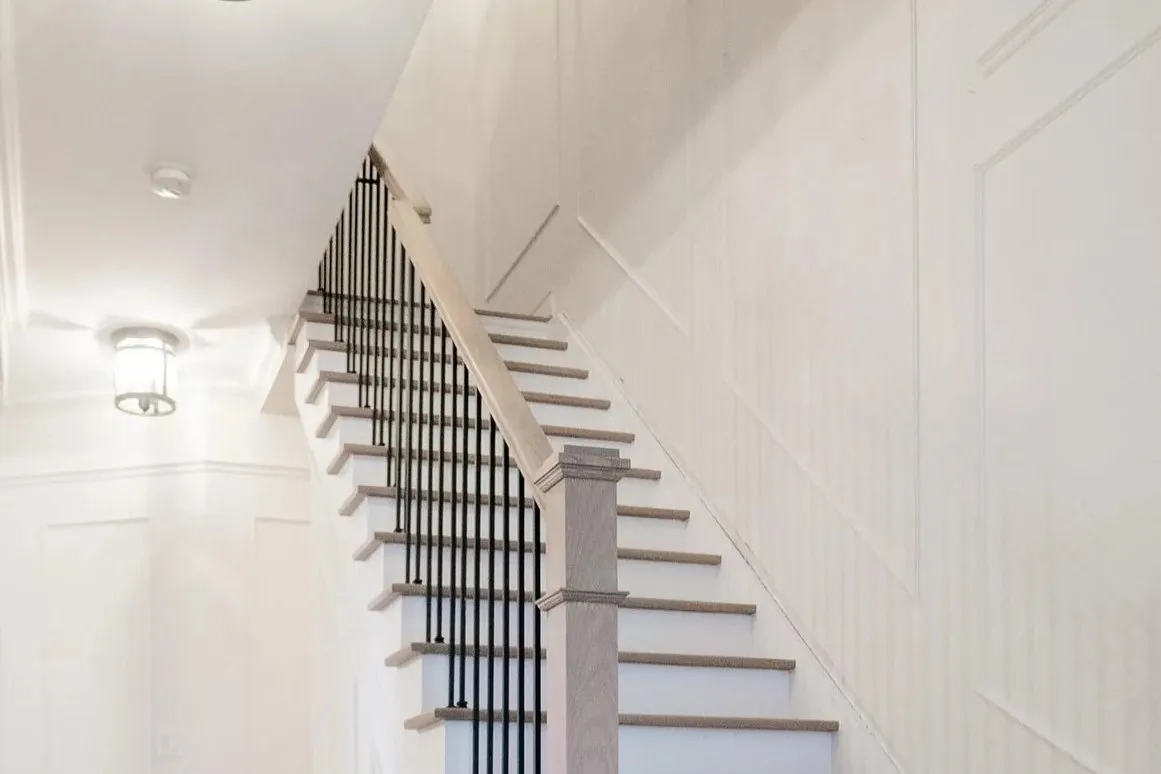 Long straight staircase in Markham with light treads, white risers and black iron spindles