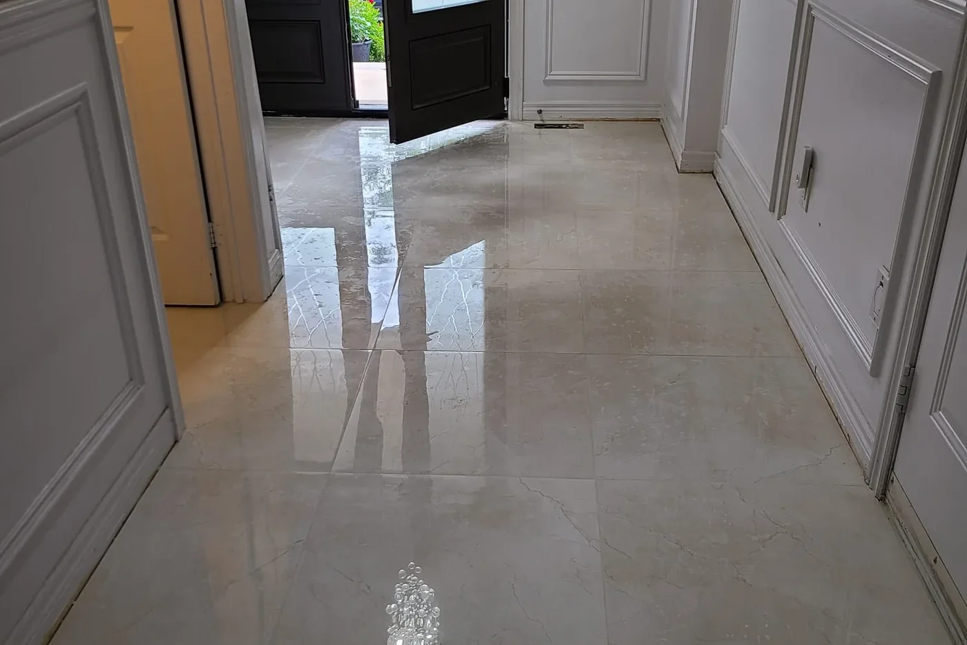 Polished cream marble-look floor tile in a front entry hallway with white wainscoting