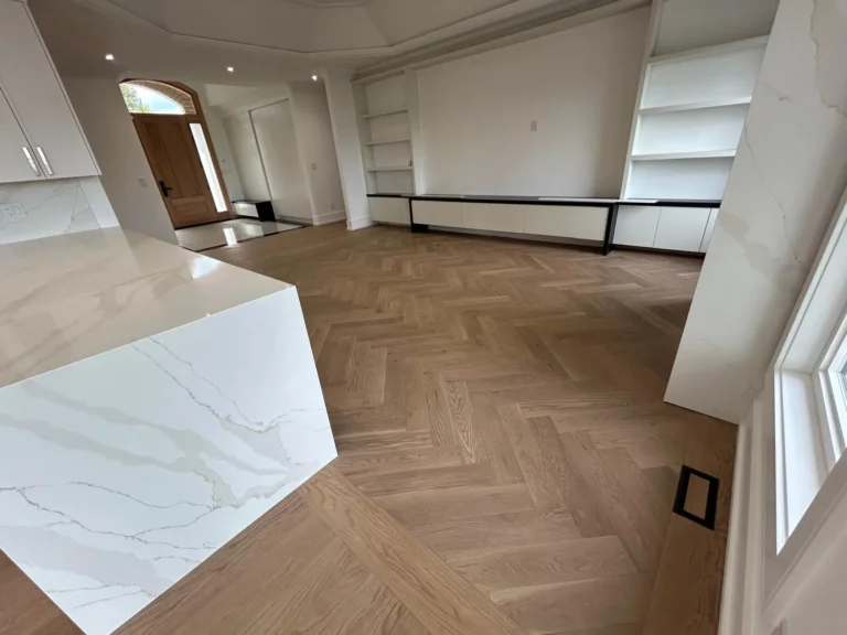 White oak herringbone hardwood floor beside a white waterfall island in a Toronto home