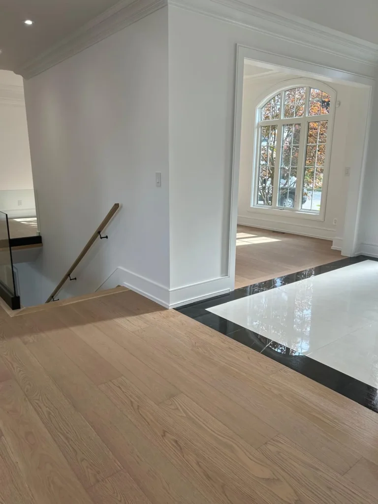 White oak hardwood meeting a polished tile foyer next to the stairs in a Toronto home