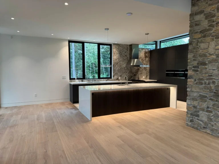 Wide plank white oak hardwood in a modern Toronto kitchen with a waterfall island and a stone feature wall