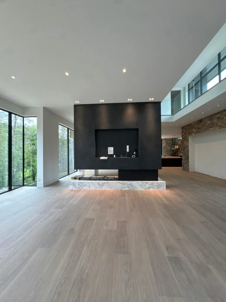 Wide plank white oak hardwood in a modern Toronto great room with floor-to-ceiling windows and a black fireplace